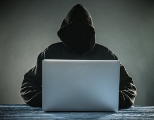 A hacker with a hood with laptop. Online network danger.